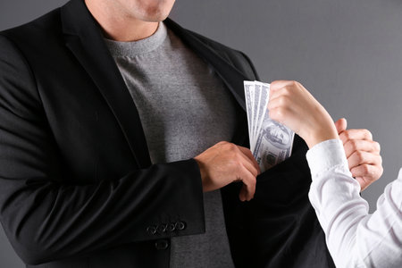 Woman giving bribe money to man on dark background, closeupの写真素材