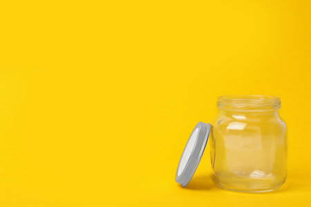 Open empty glass jar on yellow background, space for textの写真素材