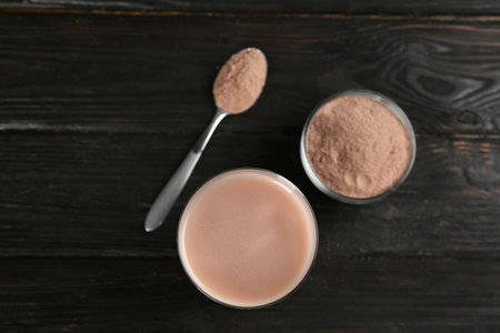 Protein shake and powder on black wooden table, flat layの写真素材