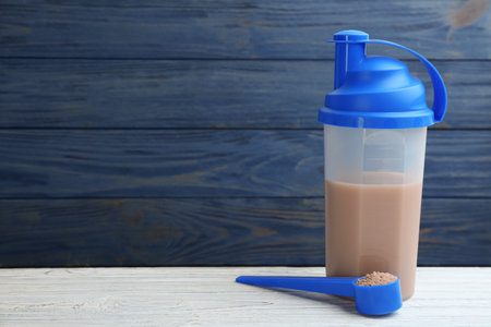 Protein shake and powder on wooden table, space for text