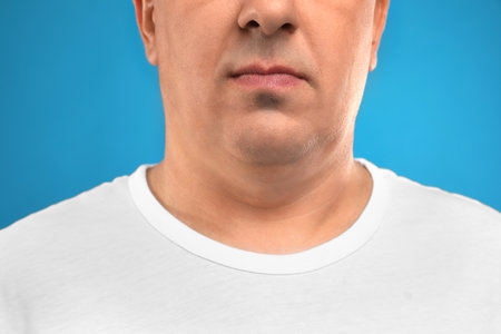 Mature man with double chin on blue background, closeupの写真素材