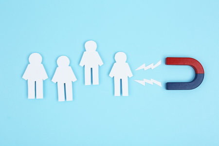 Magnet attracting paper people on light blue background, flat layの写真素材
