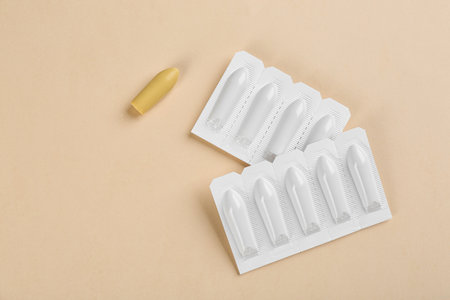 Suppositories on beige background, flat lay. Hemorrhoid treatment