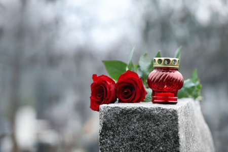 Red roses and candle on gray granite tombstone outdoors. Funeral ceremonyの写真素材