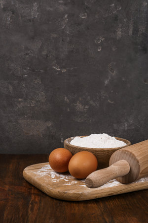 Raw eggs, flour and rolling pin on wooden table. Baking-pie
