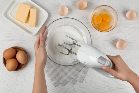 Woman whipping egg whites at wooden table, top view. Baking-pie