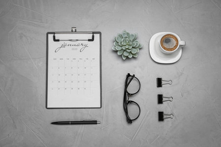 Flat lay composition with calendar and cup of coffee on gray table