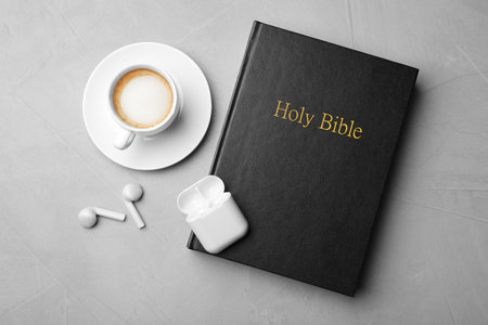 Bible, cup of coffee and earphones on light gray background, flat lay. religious audiobookの写真素材