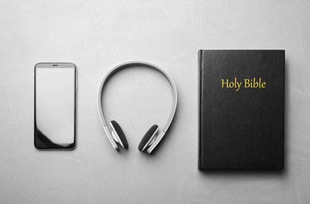 Bible, phone and headphones on light gray background, flat lay. religious audiobookの写真素材