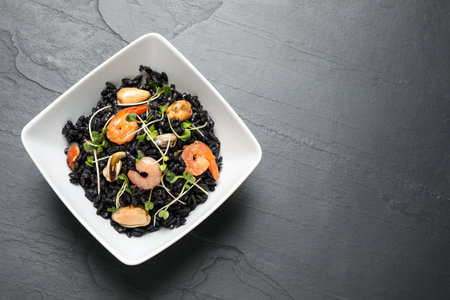 Delicious black risotto with seafood in bowl on gray table, top view. Space for textの写真素材