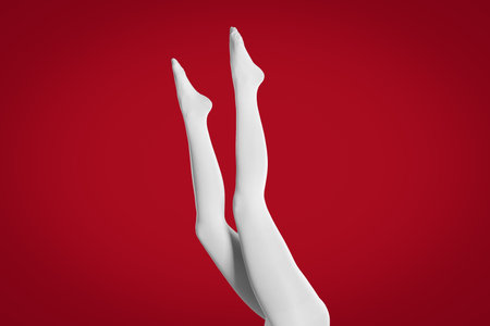 Woman wearing white tights on red background, closeup of legsの写真素材