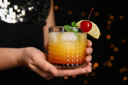 Woman with glass of Tequila Sunrise on blurred background, closeup. Delicious alcoholic cocktailの写真素材