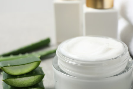 Open jar of cream and cut aloe on table, closeup. organic cosmeticsの写真素材