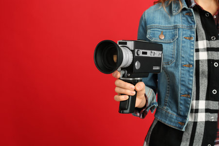 Woman with vintage video camera on red background, closeup. Space for text