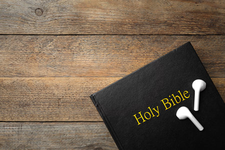 Bible and earphones on wooden background, top view with space for text. religious audiobookの写真素材