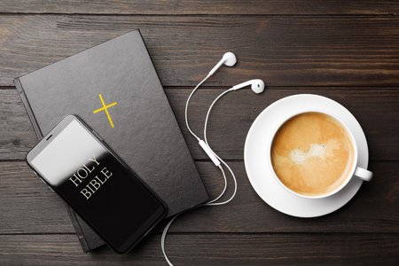Bible, phone, cup of coffee and earphones on wooden background, flat lay. religious audiobookの写真素材