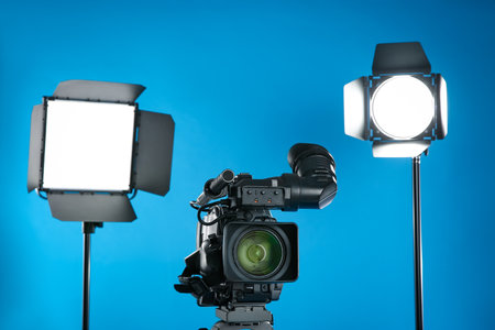 Professional video camera and lighting equipment on blue backgroundの写真素材