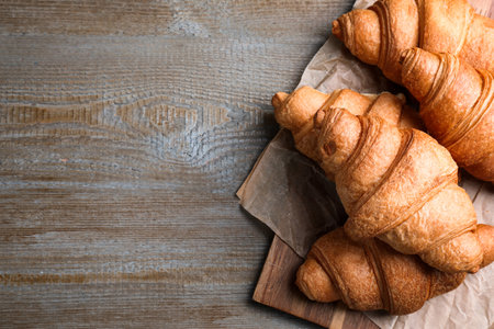 Tasty fresh croissants on wooden table, top view. Space for textの写真素材