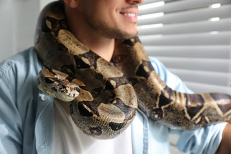 Man with his boa constrictor at home, closeup. exotic petの写真素材