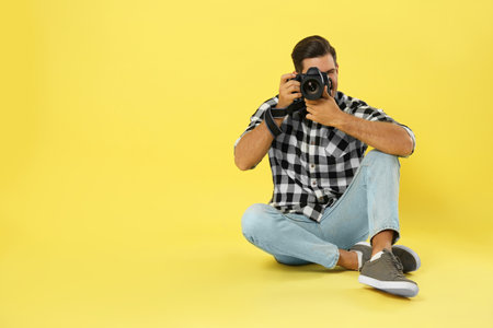 Professional photographer working on yellow background in studio. Space for text