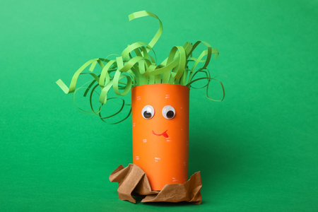 Toy carrot made of toilet paper hub on green backgroundの写真素材