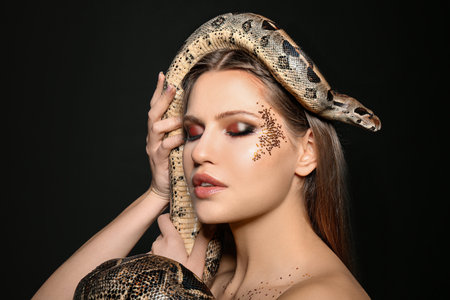 Beautiful woman with boa constrictor on black backgroundの写真素材