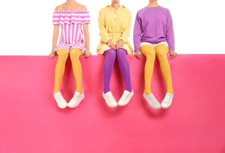 Group of women wearing bright tights and stylish shoes sitting on color background, closeupの写真素材
