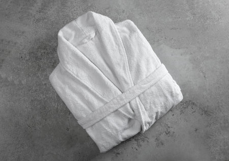 Clean folded bathrobe on gray stone background, top view