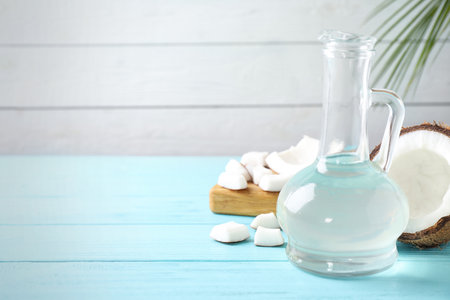 Coconut and jug with oil on light blue wooden table, space for textの写真素材