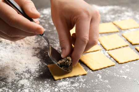 Woman making ravioli at gray table, closeup. Italian pastaの写真素材