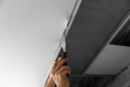 Repairman installing white stretch ceiling in room, closeupの写真素材