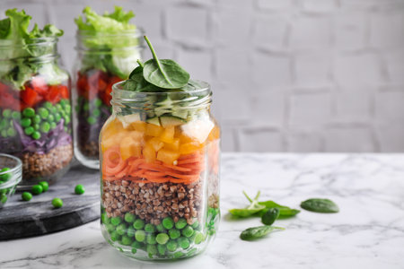 Healthy salads in glass jars on marble table. Space for textの写真素材