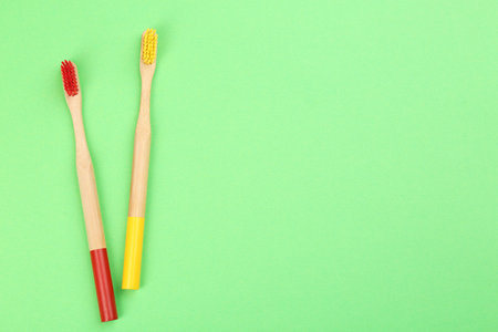 Natural bamboo toothbrushes on green background, flat lay. Space for textの写真素材