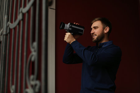 Young man with vintage video camera outdoors