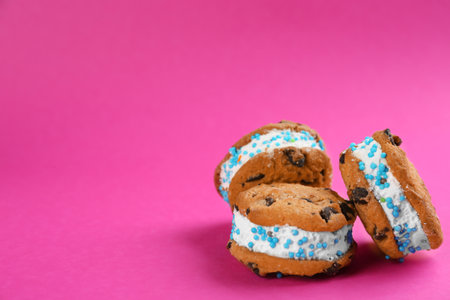 Sweet delicious ice cream cookie sandwiches on pink background. Space for textの写真素材