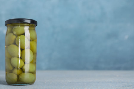 Glass jar with pickled olives on table. Space for textの写真素材
