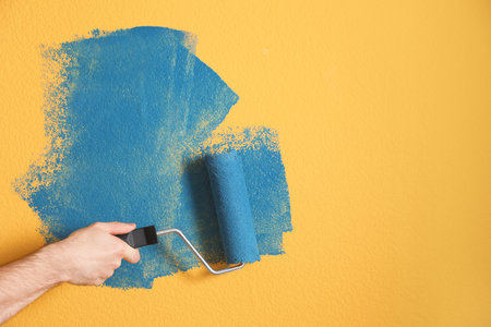 Man painting yellow wall with blue dye, closeupの写真素材