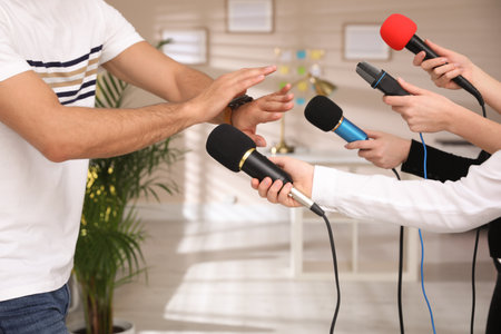 Man avoiding journalist's questions at interview indoors, closeup viewの写真素材