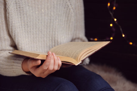 Young woman reading book at home, closeupの写真素材