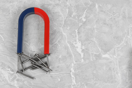 Magnet attracting nails on gray marble table, flat lay. Space for textの写真素材