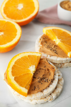 Puffed rice cakes with peanut butter and orange on white tableの写真素材