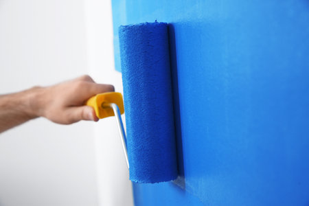 Man painting white wall with blue dye, closeup. interior renovationの写真素材