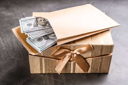 Envelope with dollar bills and gift box on gray stone tableの写真素材