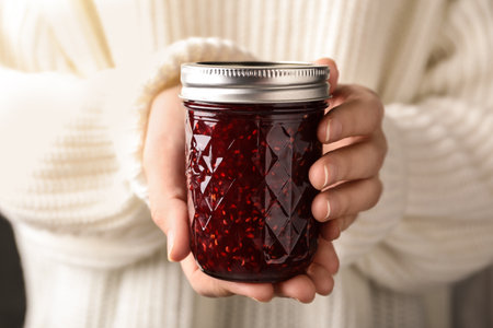 Woman with jar of raspberry jam, closeupの写真素材
