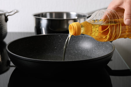 Woman pouring cooking oil from bottle into frying pan, closeupの写真素材