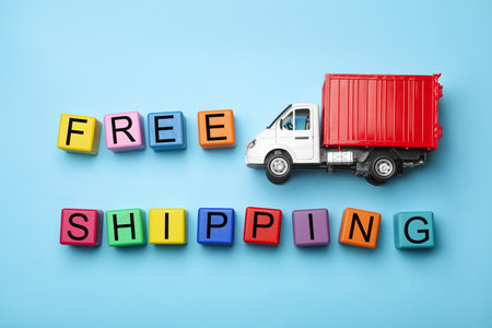 Toy truck with words FREE DELIVERY on blue background, flat lay. Logistics and wholesale conceptの写真素材