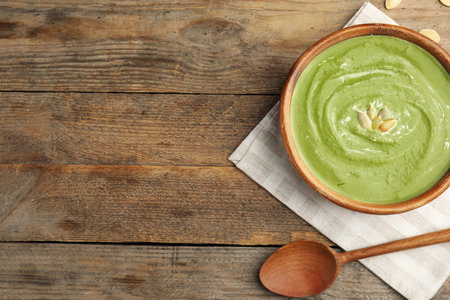Delicious broccoli cream soup served on wooden table, flat lay. Space for textの写真素材