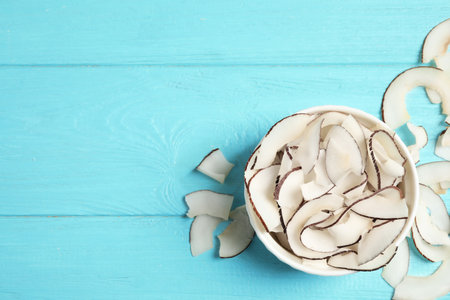 Tasty coconut chips on light blue wooden table, flat layの写真素材