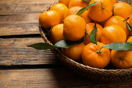 Fresh ripe tangerines with leaves on wooden table, closeup. Citrus fruitsの写真素材