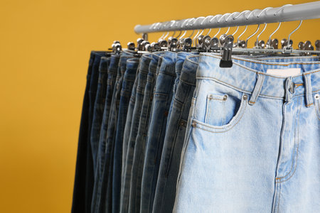 Rack with different jeans on yellow background, closeupの写真素材